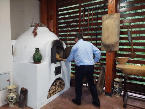 Kovács Péter polgármester kiveszi a friss kenyeret a sütőből a kertvárosi tanyaudvarban