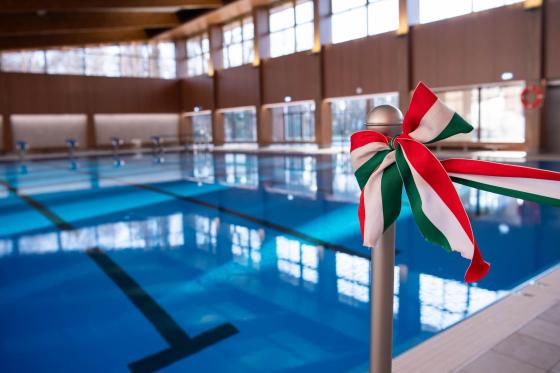 Életkép a felújított Szentmihályi Konrád Ferenc Uszoda uszodateréről, előtérben egy nemzeti színű szalagos masni.