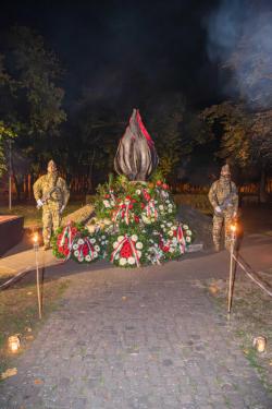 A koszorúkkal körbevett Forradalom Lángjai emlékmű
