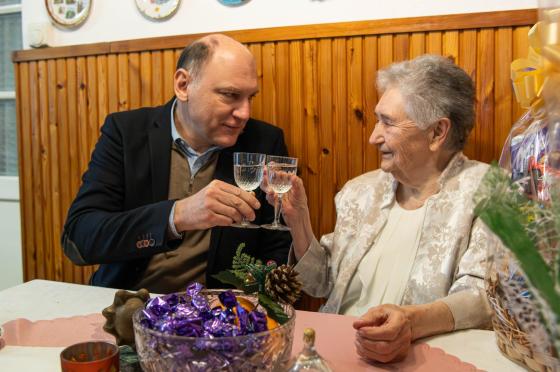 Szász József alpolgármester köszönti Dernovics Istvánné Nusi nénit köszöntötték kilencvenedik születésnapja alkalmából, pezsgővel koccintanak